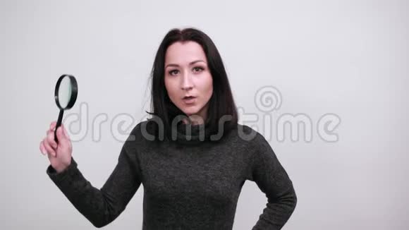 震惊的女人让放大镜靠近眼睛手握腰部视频的预览图