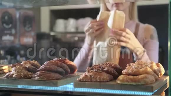 美丽的年轻女卖家在糖果店工作提供新鲜糕点卖家包新鲜面包视频的预览图