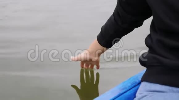小女孩轻轻地摸着湖面上的水女人在绿水上牵着手掌女人的手在公园里碰水女汉视频的预览图