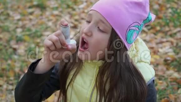 一个戴着帽子和夹克的女孩在秋林散步时以吸入剂的形式吃药治疗支气管哮喘流感视频的预览图