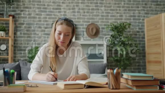 快乐的女孩完成家庭作业放松微笑坐在公寓的办公桌上视频的预览图