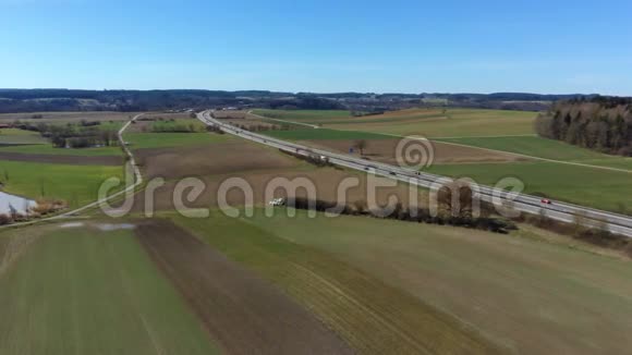 飞越高速公路附近的森林与城镇的地平线高速公路穿越绿色草地和森林的空中视频视频的预览图