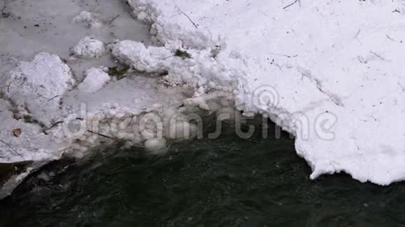 冬天雪从山溪和石急流中快速流出的水瀑布视频的预览图
