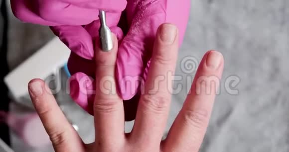 美甲师傅在粉红色手套上用电钻刮掉美甲沙龙的旧清漆美容专业美甲视频的预览图