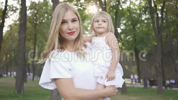 美丽的金发女人抱着小女儿而大儿子出现在他们旁边快乐母亲的肖像视频的预览图
