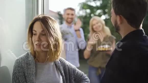 年轻的已婚夫妇在门口迎接烦人的客人友好的邻居拜访带蛋糕的男人和女人视频的预览图