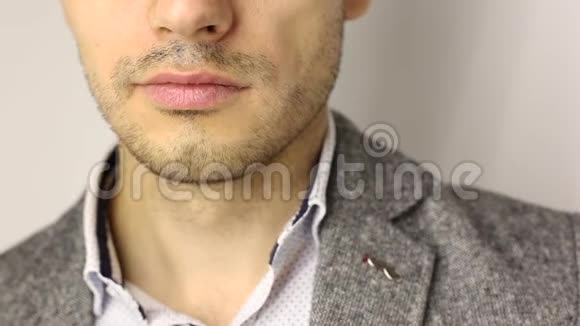 用三天胡茬在男性下巴上特写穿着灰色夹克和白色斑点衬衫的疲惫的壮汉打着哈欠没有脸视频的预览图