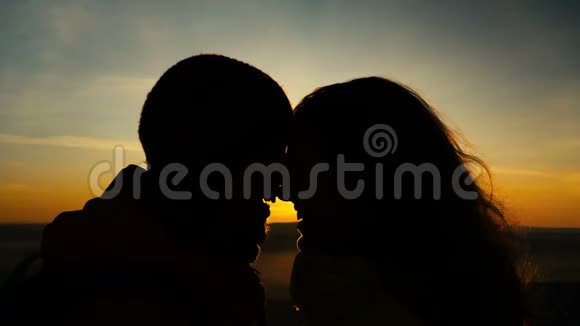 一对相爱的幸福夫妇在美丽的日落背景下接吻的剪影视频的预览图