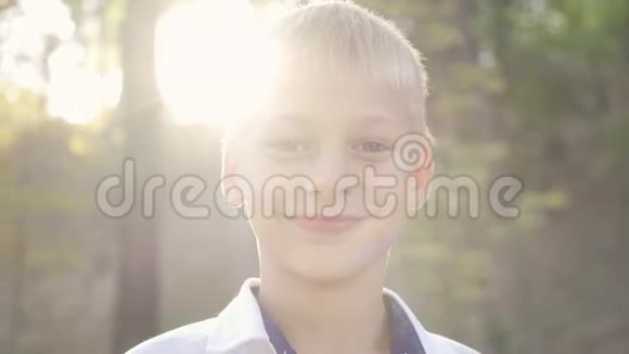 特写一个可爱的男孩看着相机微笑公园里一个孩子在阳光下的肖像休闲活动视频的预览图
