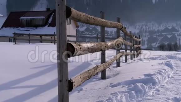 古老的废弃木栅栏雪木屋和山脉的冬季乡村景象视频的预览图