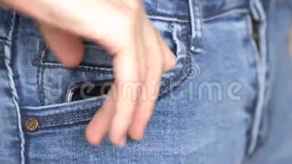 女人拿出牛仔裤口袋的黑色智能手机前视4k特写视频的预览图
