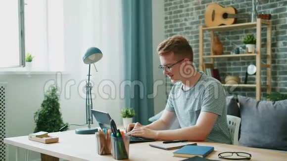 快乐的少年在家里的办公桌上用笔记本电脑打字享受交流视频的预览图