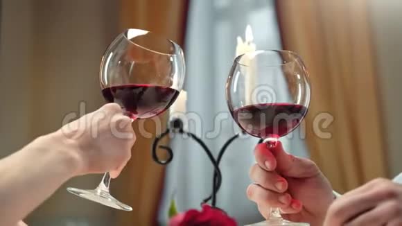 男女手捏酒杯红酒庆祝周年近距离拍摄4k红色相机视频的预览图