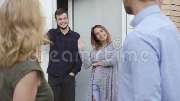 已婚夫妇离开家时他们的朋友挥手友好的邻居拜访年轻男女的家视频的预览图
