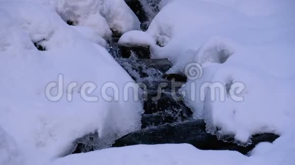 冬林中的山溪山河在冬季的冰雪中流淌视频的预览图