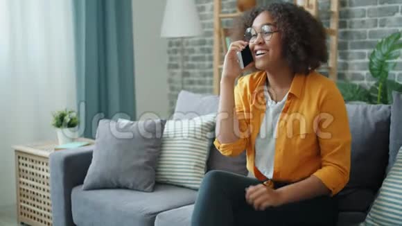 美国黑人妇女在家里用手机笑的慢动作视频的预览图