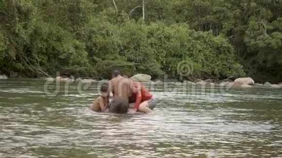一个土著男孩和一个外国男人正在水中玩着漂浮的轮胎视频的预览图