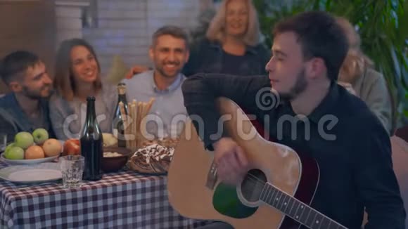 年轻的白种人弹吉他招待朋友人们一起度过夜晚视频的预览图