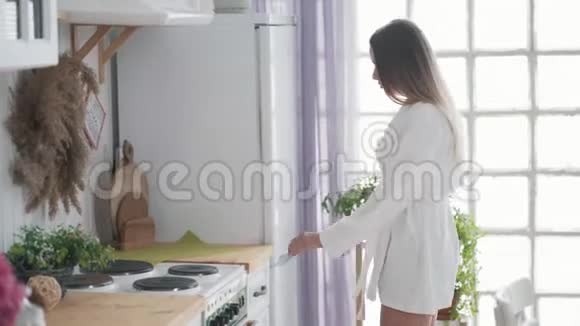 年轻女子打开厨房的橱柜拿出毛巾和水壶视频的预览图