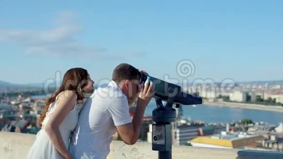 男青年带着女人在观景点用Coin操作的双眼看城市之美视频的预览图