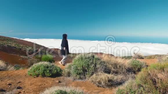 年轻的自由女子在山峰上张开双臂动力和灵感在云层之上向上攀爬手臂视频的预览图