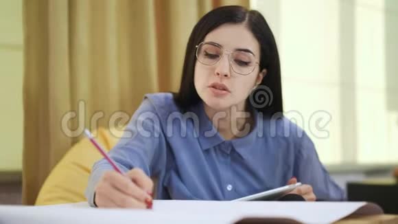 穿着蓝色衬衫和眼镜的年轻女子在同事间写作视频的预览图