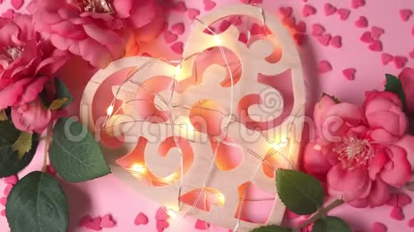 木制的心与灯光花环躺在粉红色的背景与心和花视频的预览图