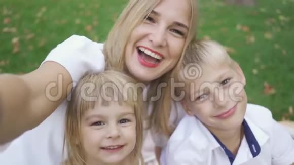 年轻的白种人女人和两个孩子在公园里自拍妈妈带着孩子笑妈妈在和她的孩子说话视频的预览图
