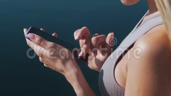 关闭女性手在手机上键入文本信息在背景上显示海视频的预览图