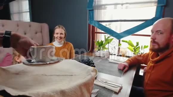 一个成功的家庭坐在酒店的餐馆里一个服务员把咖啡杯带到桌子上视频的预览图
