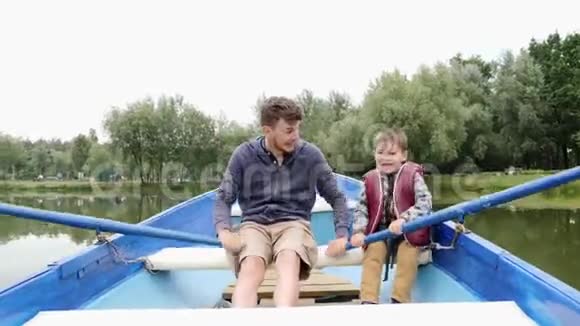 快乐的父子在公园的湖上享受乘船旅行快乐的家庭一起在户外度过时光父亲和孩子玩游戏视频的预览图