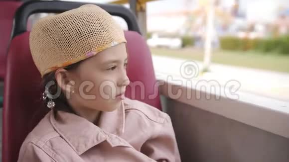 小女孩裹着一件夹克在公共汽车上没有窗户看着外面视频的预览图