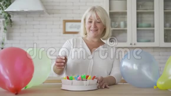 一位资深妇女为她的孩子或孙子准备蛋糕的肖像生日庆祝概念可爱的奶奶视频的预览图