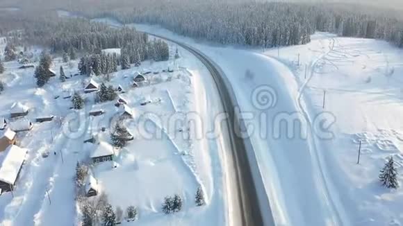 公路穿越冬林航拍无人机公路附近的一个积雪覆盖的小村庄雪视频的预览图