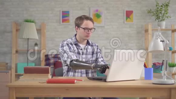 有仿生假肢的青年学生在笔记本电脑上工作视频的预览图