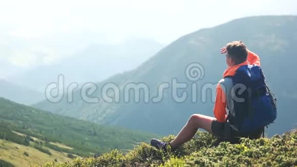 徒步旅行者坐在山上欣赏群山视频的预览图