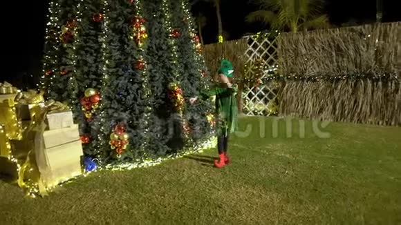 快乐可爱的女孩穿着精灵服装跳舞在圣诞树附近唱歌圣诞老人助手庆祝圣诞节为圣诞节感到高兴视频的预览图