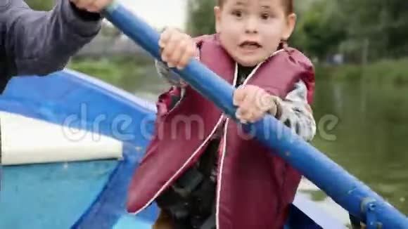 可爱的小孩在湖上对着镜头说话和微笑可爱的孩子在公园的木船上航行可爱的小男孩视频的预览图