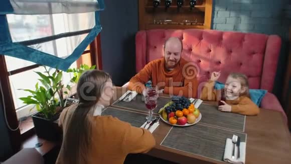 一家人坐在酒店的餐厅里用无酒精饮料干杯视频的预览图
