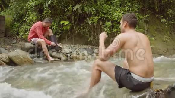 男人鼓励他的朋友把他受伤的脚放在河里视频的预览图