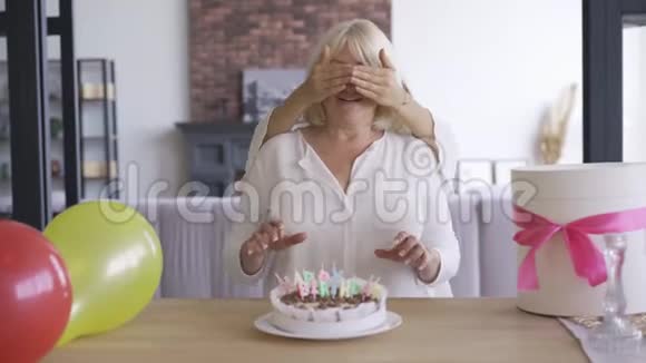 女儿为母亲办生日聚会年轻女子在给妈妈看蛋糕和蛋糕前遮住眼睛视频的预览图