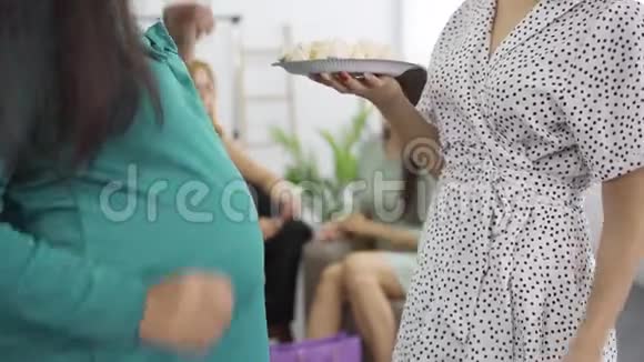 一个两个高加索女人的特写抚摸她们的肚子品尝糖果期待的女人和她的朋友享受视频的预览图