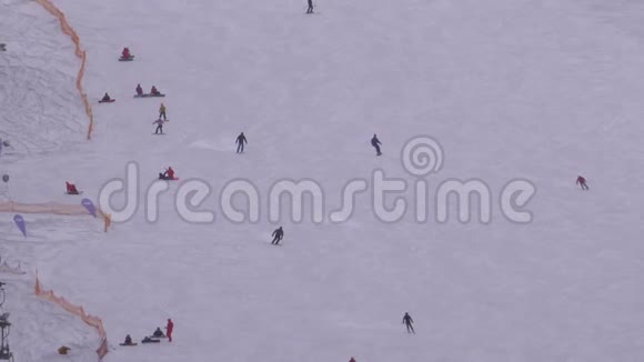 在阳光明媚的日子里滑雪者和滑雪者在滑雪场的雪坡上骑行视频的预览图