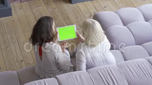 年轻女子坐在沙发上的俯视图显示了她在平板电脑上的东西友好家庭视频的预览图