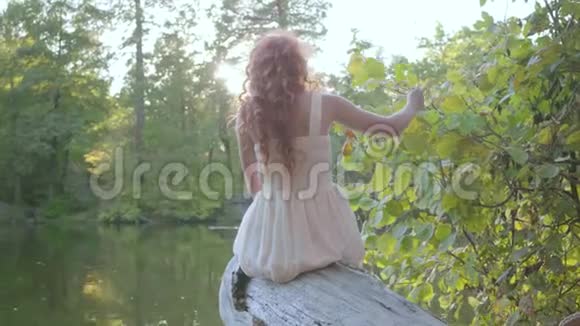在河岸边坐着一头红发的美丽白种人女人的后景户外休闲连接视频的预览图