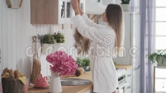 年轻女子打开厨房的橱柜拿出一罐食物视频的预览图
