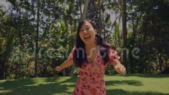 慢动作户外生活方式万向节拍摄年轻美丽快乐的亚洲女性兴奋地在草地上奔跑视频的预览图