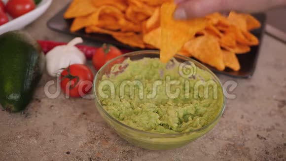 手舀鳄梨酱与美味的玉米饼片视频的预览图