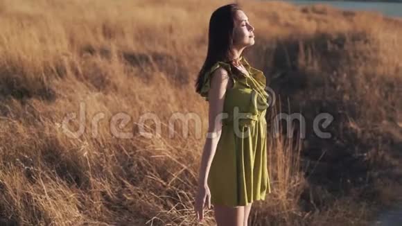 美丽的女人在日落时分站在田野里深呼吸慢动作视频的预览图
