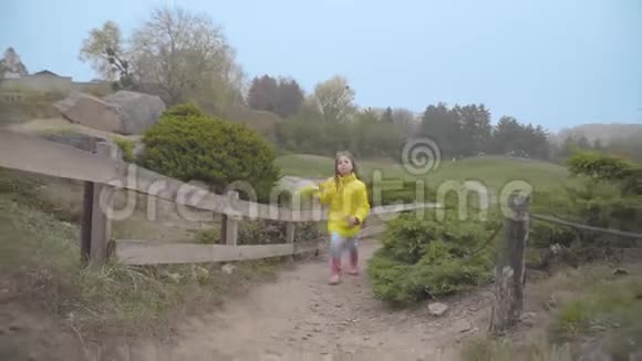 穿着黄色外套的白人女孩在秋天公园的篱笆上跳跃她的杜宾头出现在右边视频的预览图